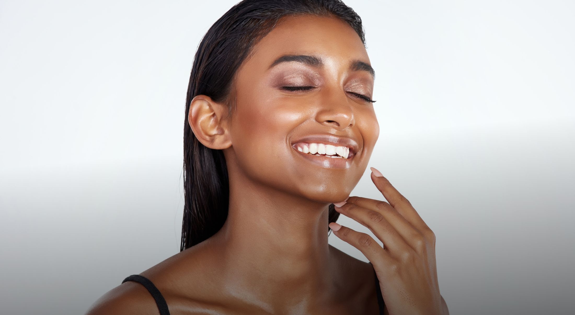 Smiling woman with glowing skin and wet hair.